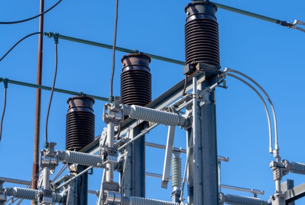 High-voltage substation equipment and insulators beneath a blue sky (stock photograph).