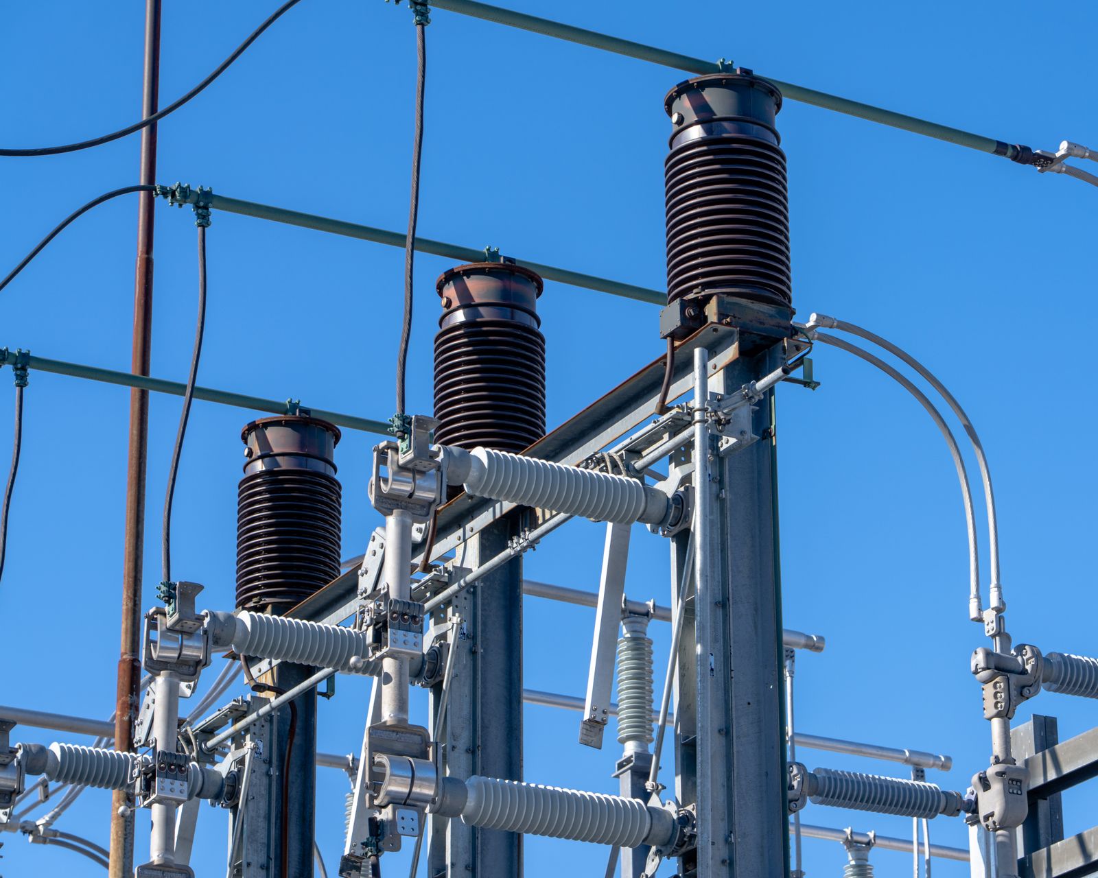 High-voltage substation equipment and insulators beneath a blue sky (stock photograph).